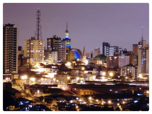 Vista, à noite, de uma cidade, com vários prédios e algumas casas.